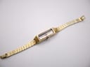 Full length, slightly angled view of the vintage Seiko watch on a clear stand, showcasing the gold-tone bracelet.