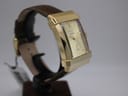 Another angled side view of the XO RETRO watch, focusing on the curved crystal and the substantial gold-tone case, with the brown leather strap visible.