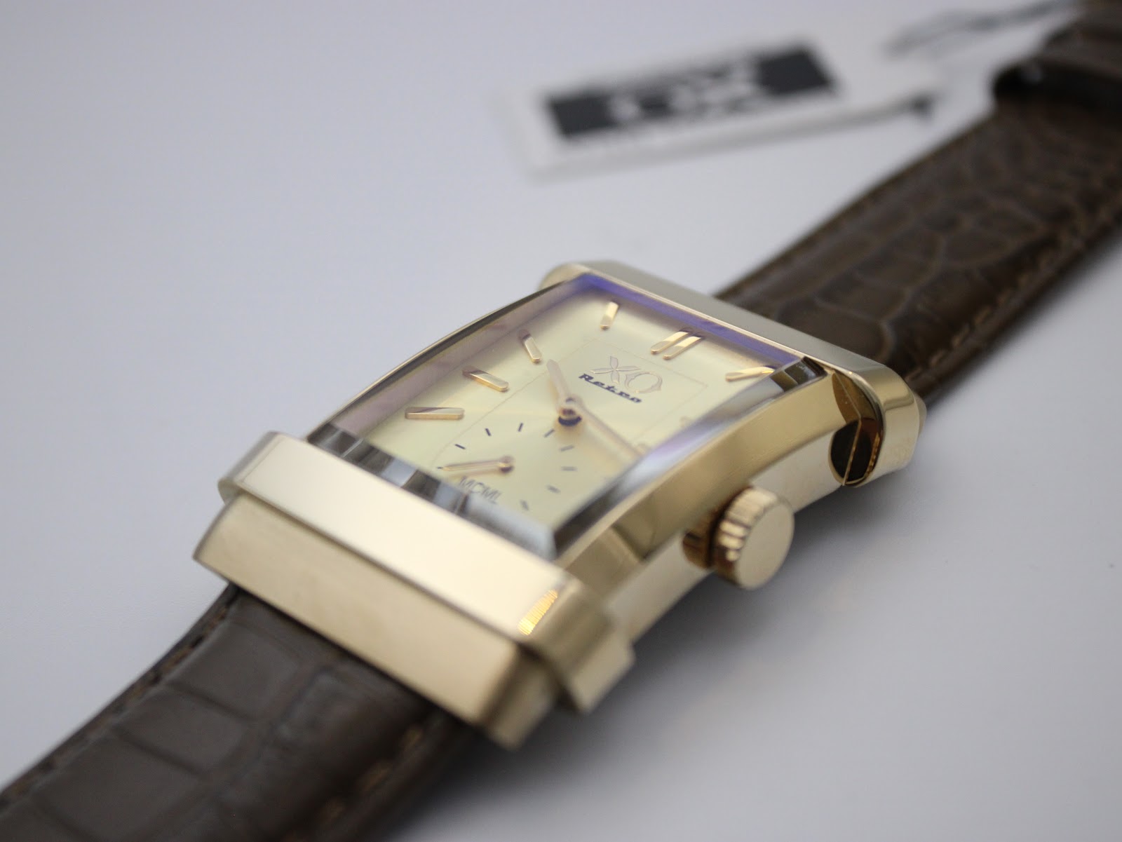 Close-up of the XO RETRO watch dial and case from an angle, showing the gold baton indices, hands, and the subtle texture of the cream dial.