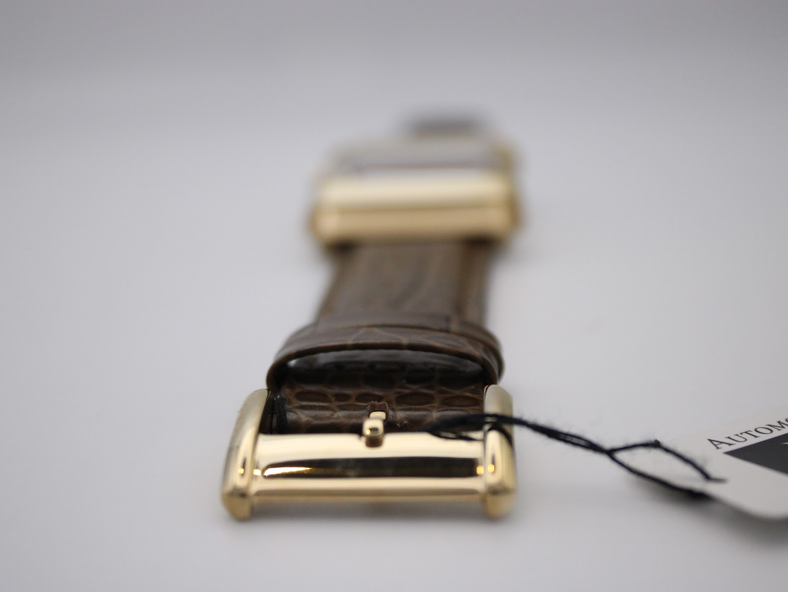 Close-up of the gold-tone pin buckle on the brown leather strap, showing its polished finish.