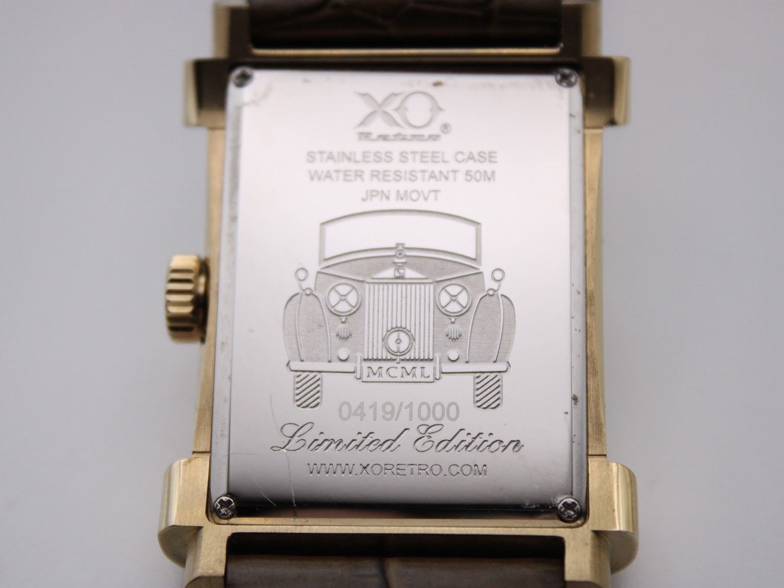 Detailed view of the watch's stainless steel case back, engraved with "XO Retre", "Stainless Steel Case", "Water Resistant 50M", "JPN MOVT", a classic car outline, "MCML", "0419/1000 Limited Edition", and "www.xoretro.com".