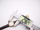 Digital caliper measuring the case diameter of the Raymond Weil 9940 watch, with the display showing a precise measurement of 24.64mm.