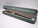 The Raymond Weil watch neatly presented in an open, dark green long display box with a contrasting cream interior.