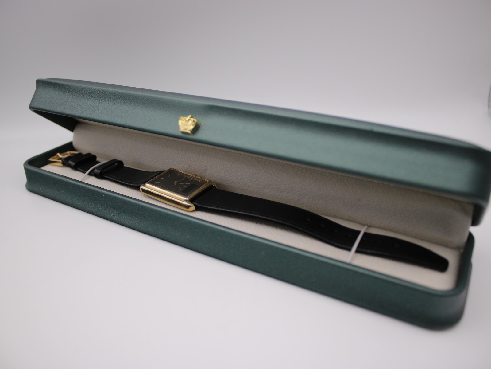 The Seiko E029-5540 watch resting neatly inside a green presentation box, showcasing its gold case and black strap.