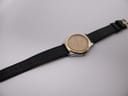 Full length view of the Tissot PRX P380 watch and its black leather strap laid out on a white background.