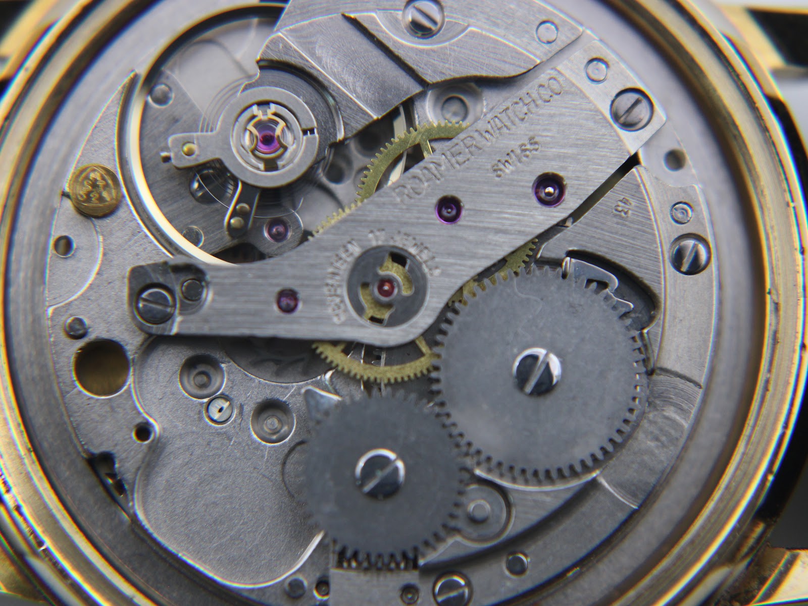 Detailed view of the Roamer watch's manual wind movement, showing gears and 'Roamer Watch Co Swiss Seventeen 17 Jewels' engraving.