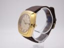 Angled side view of the Certina 288 watch, showing the right side of the gold-plated case and crown, with the brown leather strap on a stand.