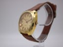 Angled view of the gold Eterna watch showing the tonneau case and dial texture with crown.