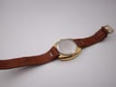 View of the Eterna watch case back and brown leather strap, showing the brushed stainless steel back.
