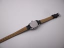 Underside view of the black leather watch strap, showing 'CALF GRAIN 10 R' marking and the silver tone buckle.