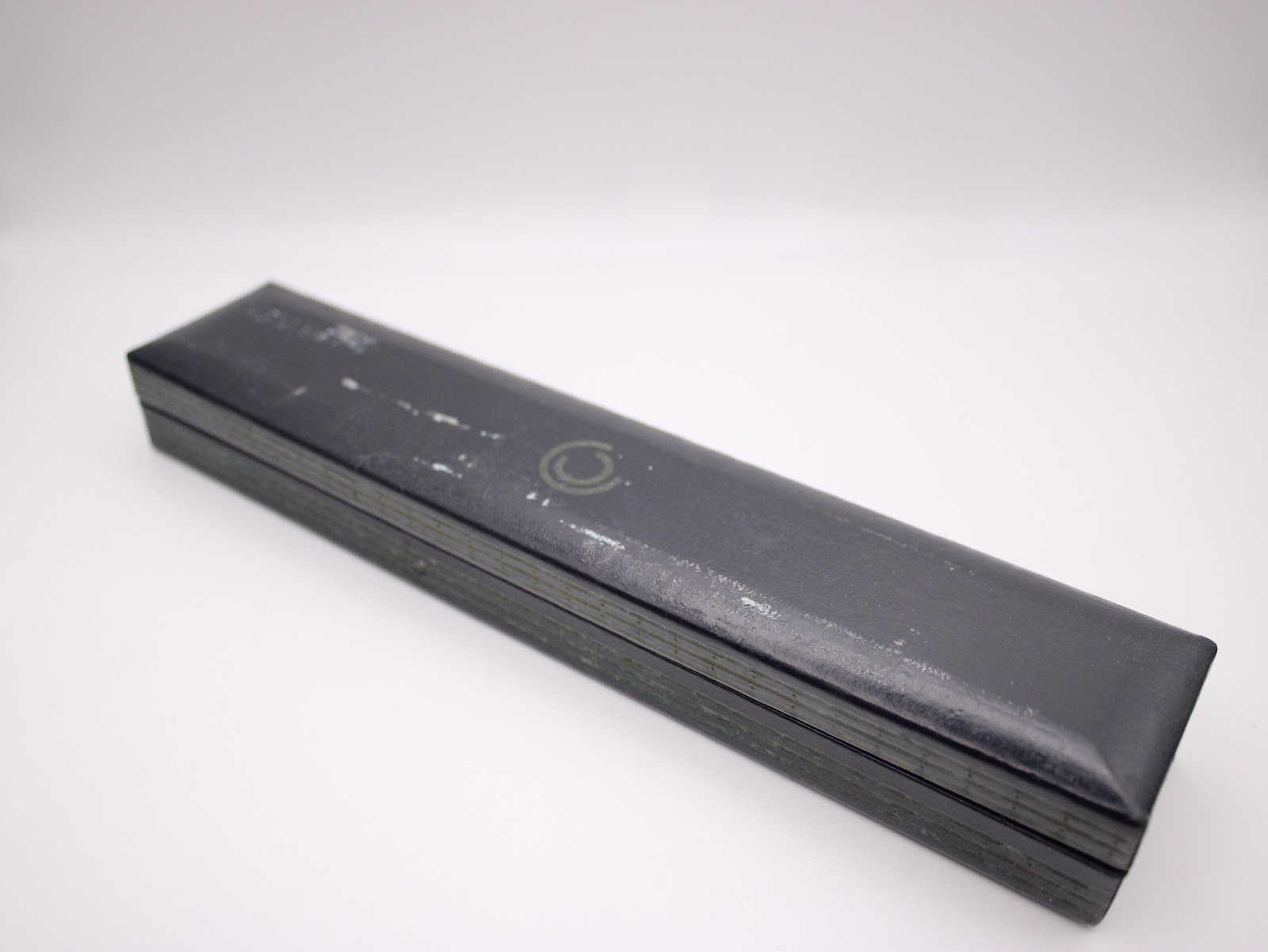 Closed original Certina watch box in dark green with a subtle logo, showing some wear on its surface.