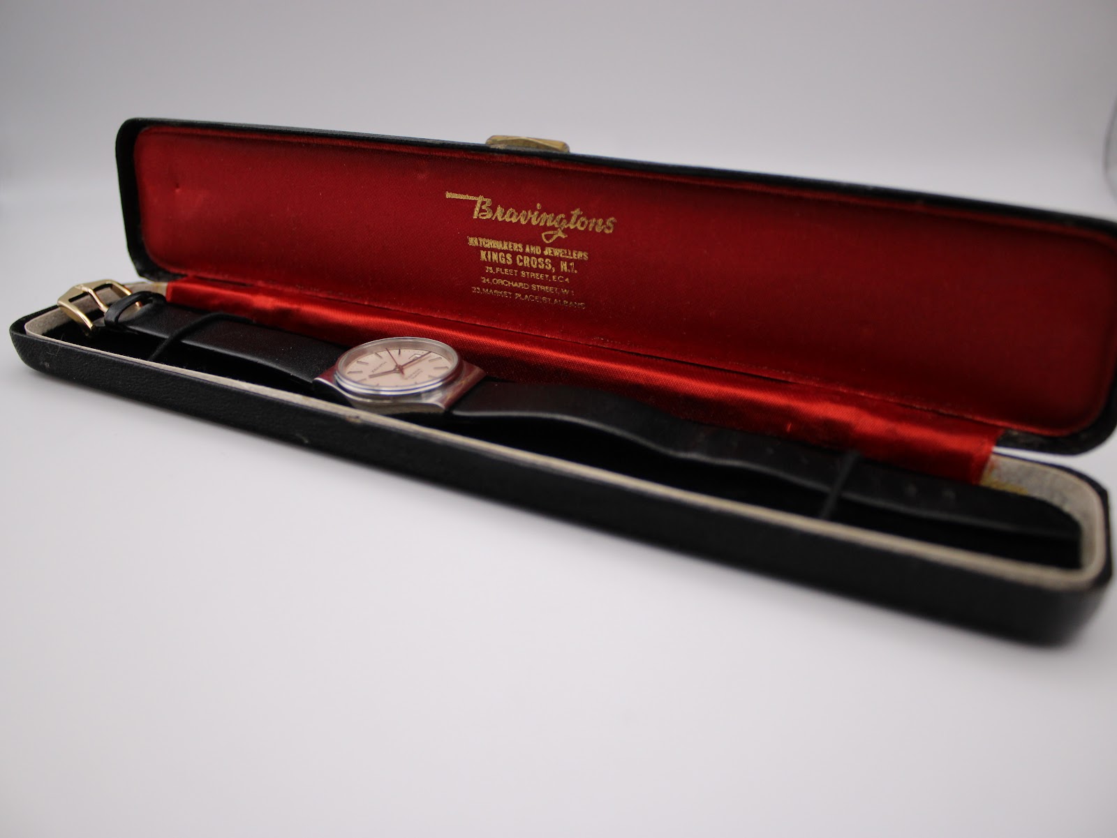 Watch inside a generic black Bravingtons watch box with red satin lining, angled view.
