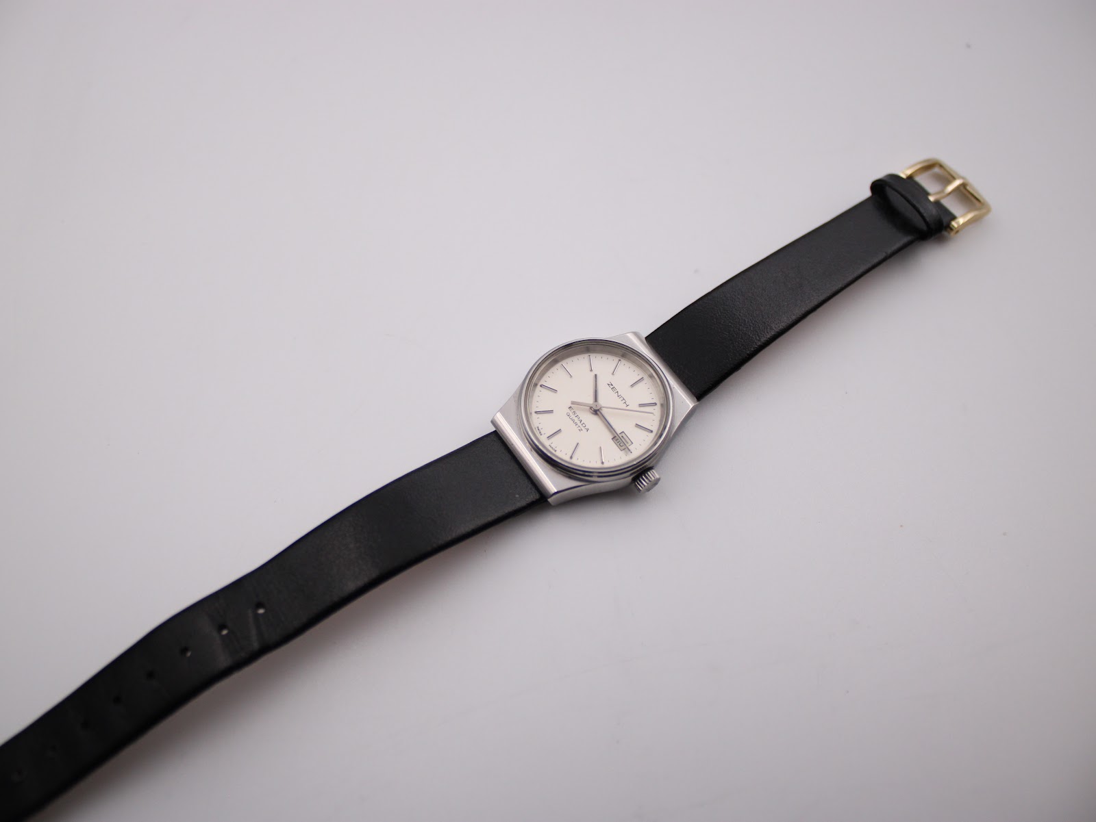 Full view of the Zenith Espada watch with its black leather strap laid flat, showcasing the gold-tone buckle.