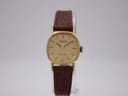 Front view of the Rado Silhouette watch on a clear display stand, showcasing its gold dial and brown lizard-grain leather strap.