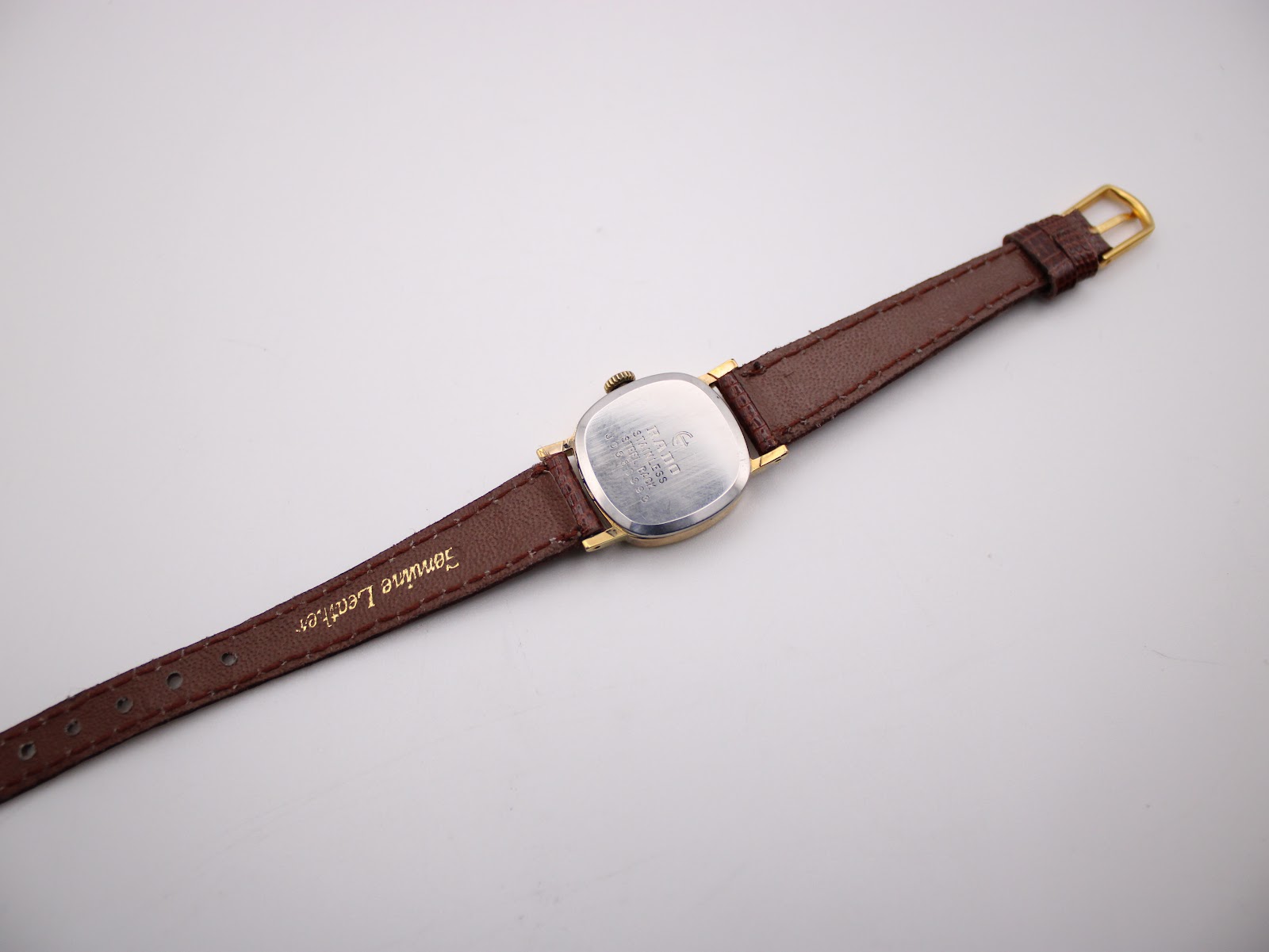 Rear view of the watch strap, showing the 'Genuine Leather' stamp on the brown lizard-grain material.