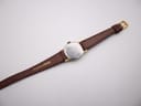 Rear view of the watch strap, showing the 'Genuine Leather' stamp on the brown lizard-grain material.