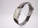 Right-side view of the PRONTO watch showing the crown, rectangular silver case, and strap.
