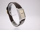 Left-side view of the PRONTO watch highlighting the rectangular case profile and brown strap on a stand.