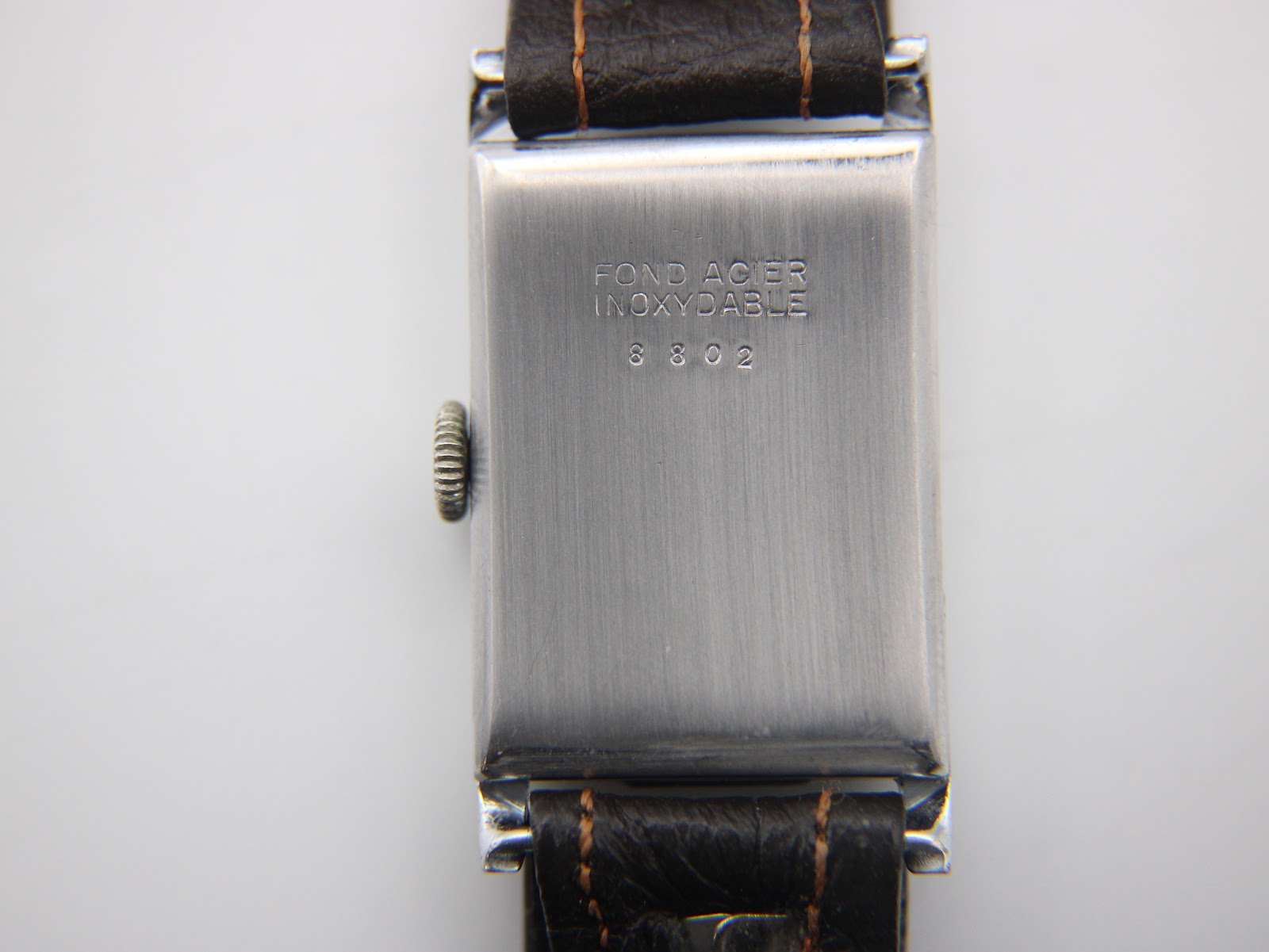Close-up of the polished stainless steel case back with "FOND ACIER INOXYDABLE" and serial number 3802 engraving.