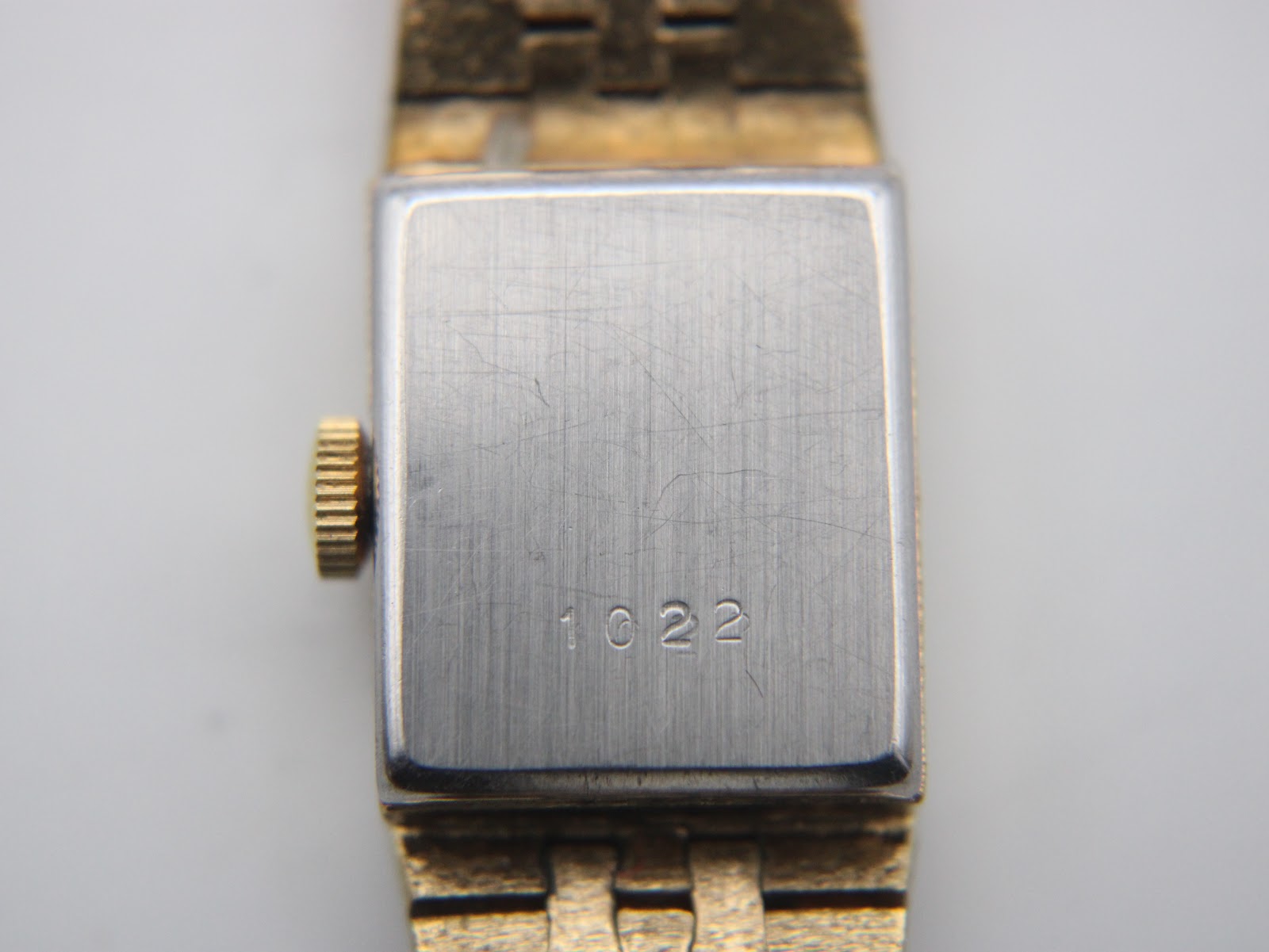 Close-up of the brushed silver-tone case back of the watch, showing the engraved model number '1022' and minor surface scratches.