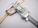 A digital caliper measuring the width of the Rotary watch case, with the display showing an exact measurement of 15.0 mm.