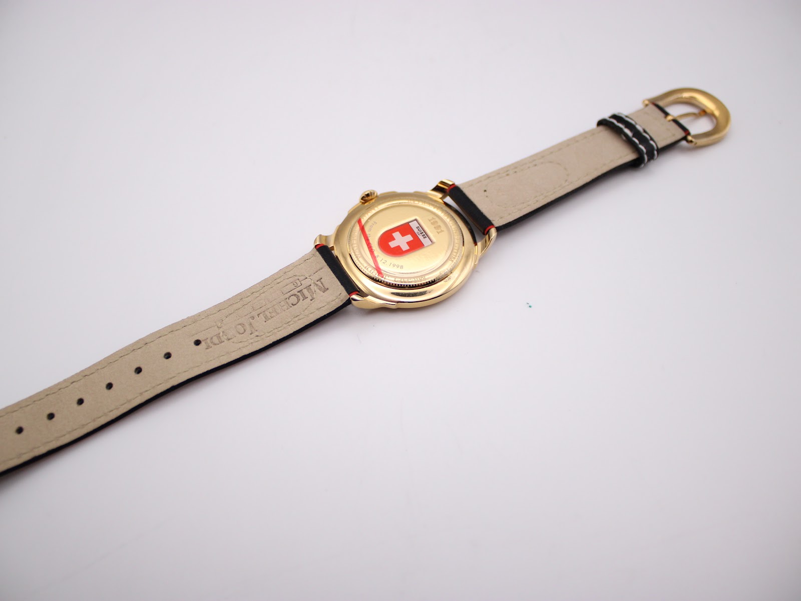 Full back view of the watch on a display stand, showing the case back details and the underside of the strap.