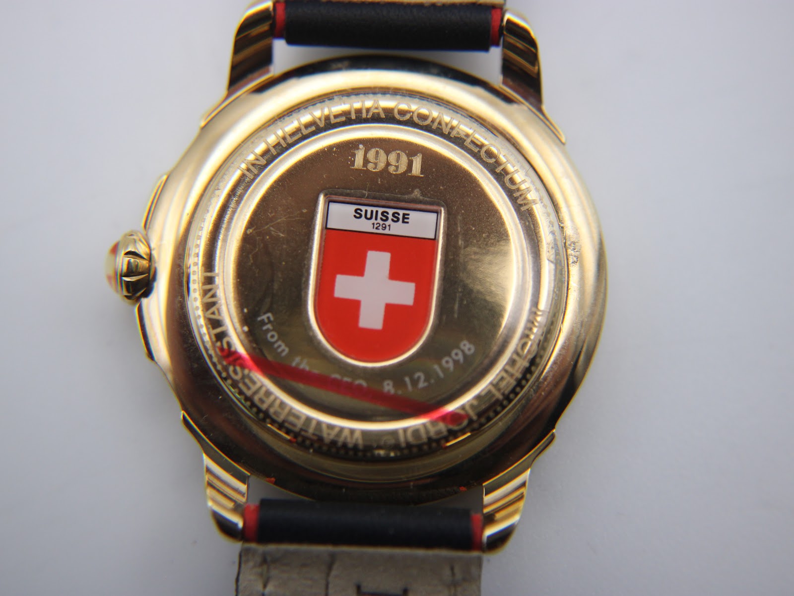 Close-up of the watch's gold tone case back, engraved with '1991', 'WATER RESISTANCE', and a Swiss shield emblem.