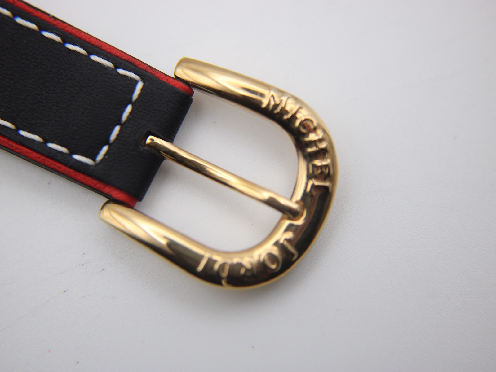 Close-up of the watch's gold tone buckle, clearly engraved with the 'MICHEL JORDI' brand name.