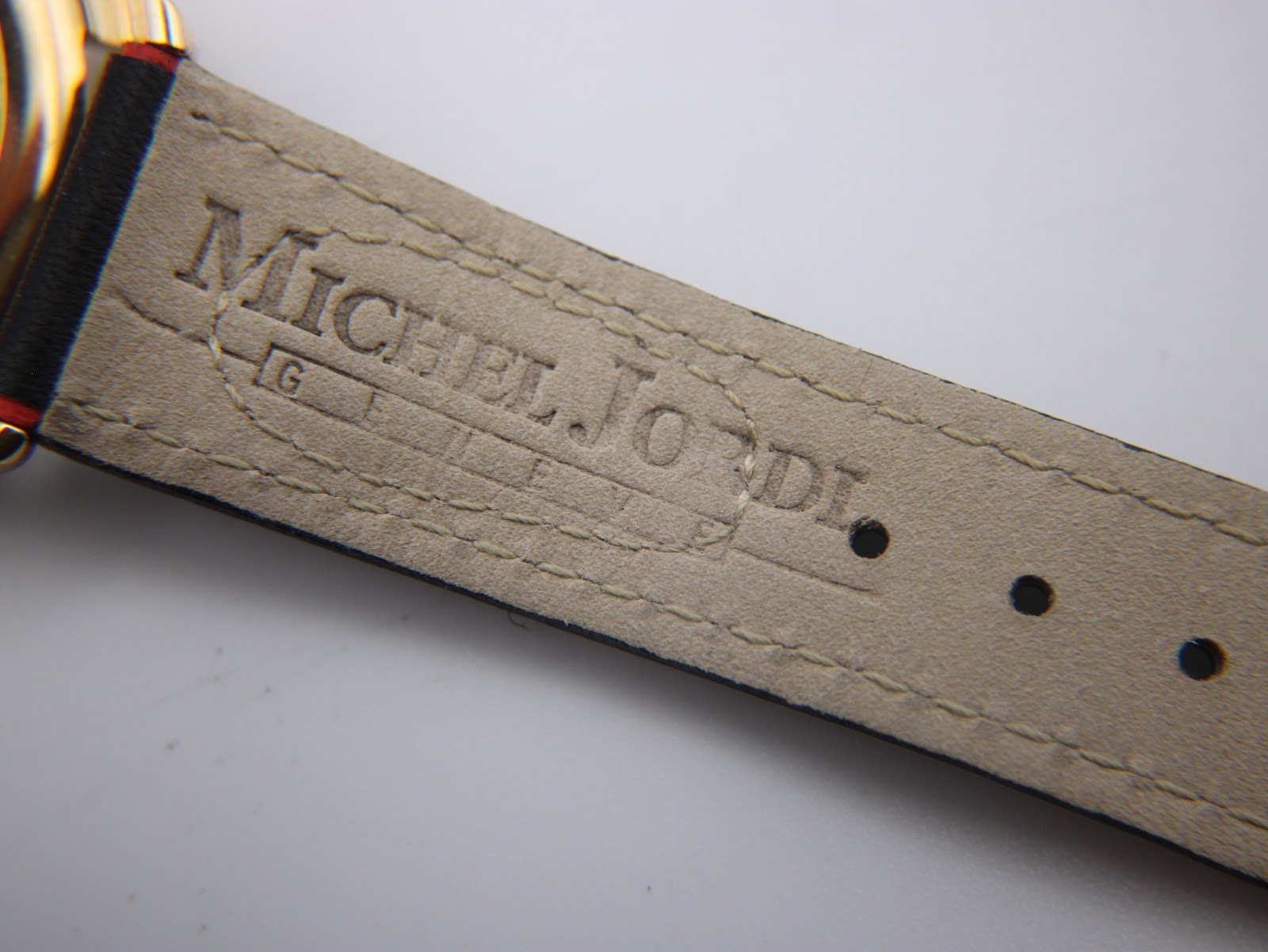 Interior view of the black leather strap, showing the embossed 'MICHEL JORDI GENEVE' text.