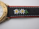 Close-up of the black leather strap's intricate embroidery, depicting white and yellow Edelweiss flowers.