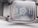 Close-up of the stainless steel case back of the Tissot watch, showing model number, serial, "sapphire crystal," and "water resistant 30m" engravings with surface scratches.