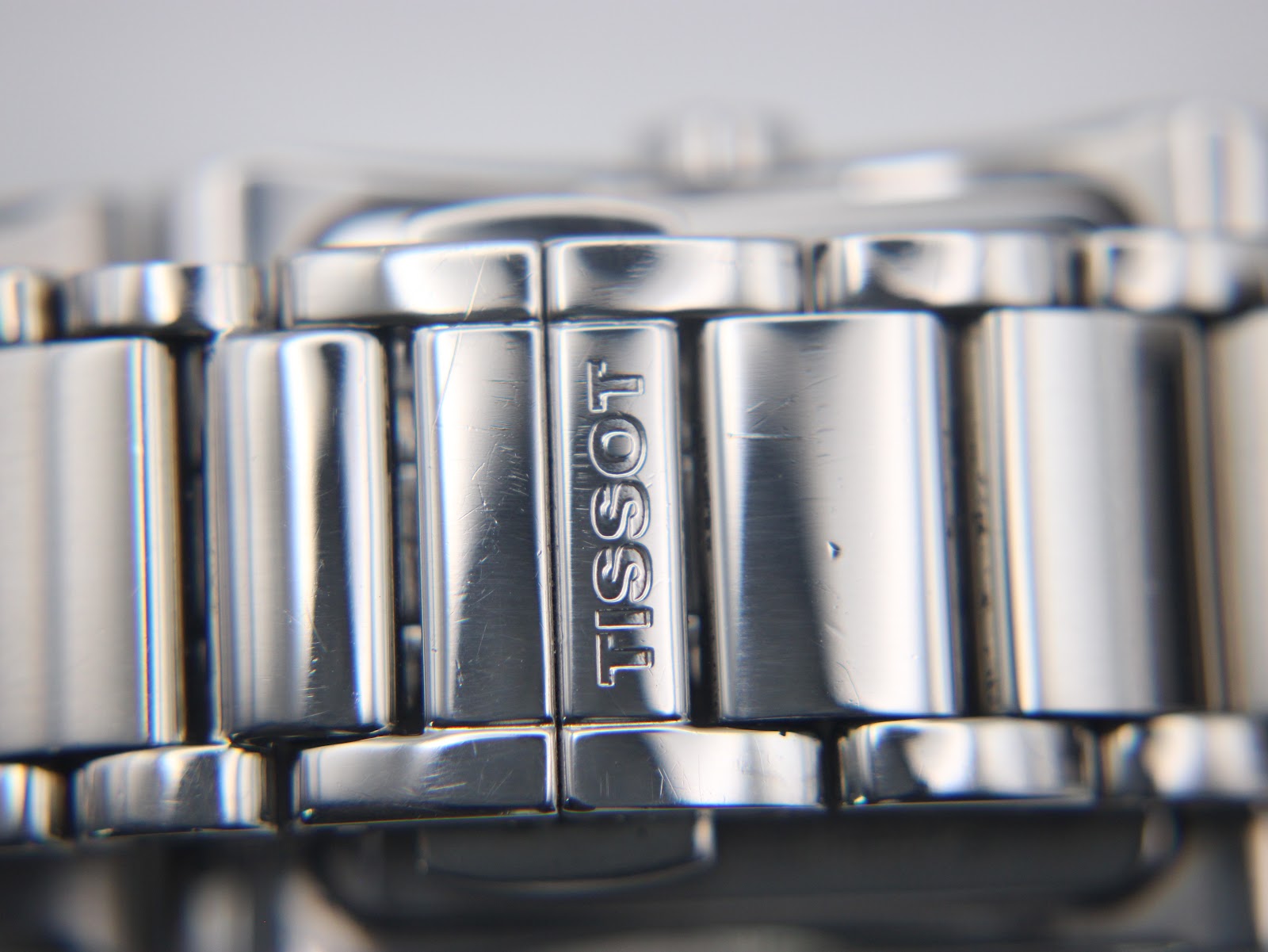 Close-up of the Tissot logo engraved on the folding clasp of the stainless steel bracelet.