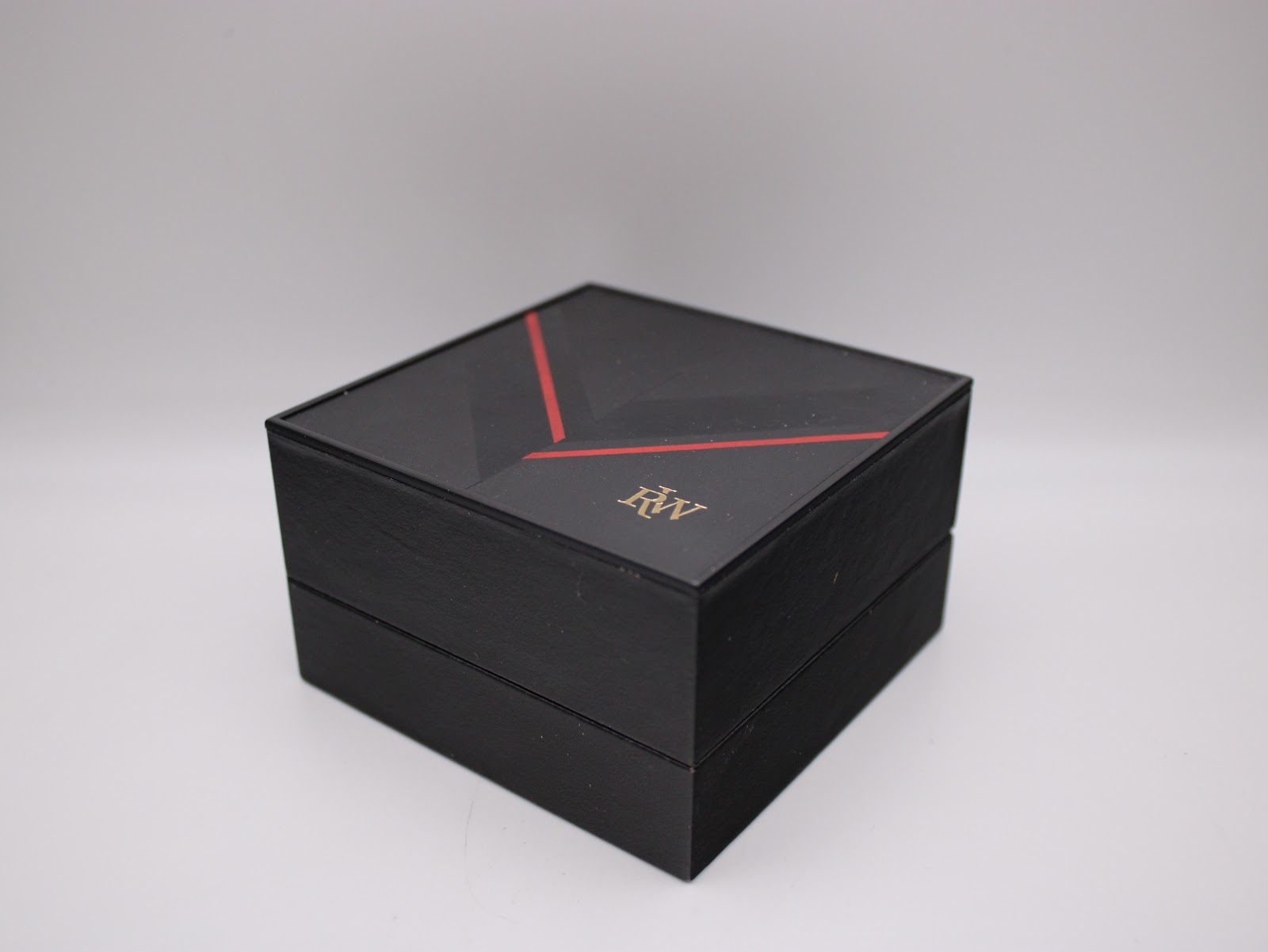Closed original Raymond Weil watch box in black with a red and gold "RW" logo.