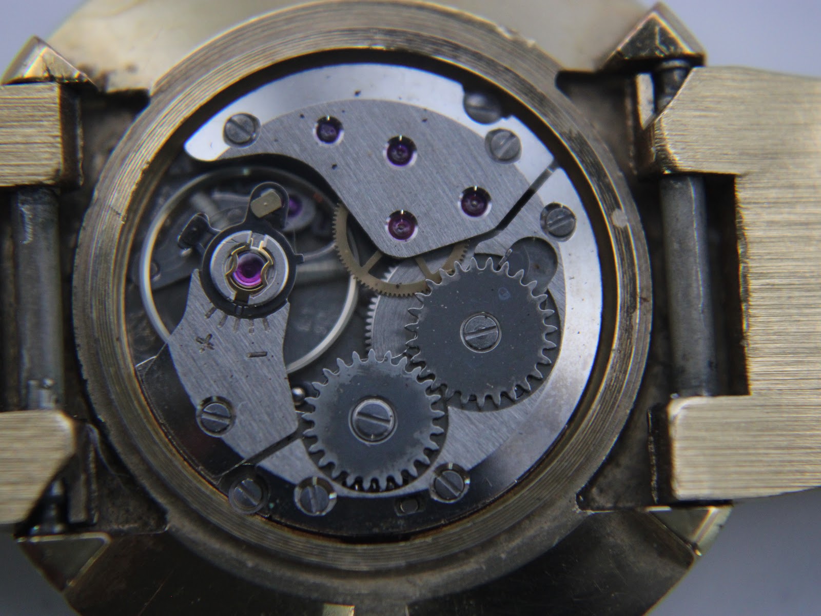 Close-up of the manual wind watch movement, revealing gears, jewels, and the intricate mechanical components.