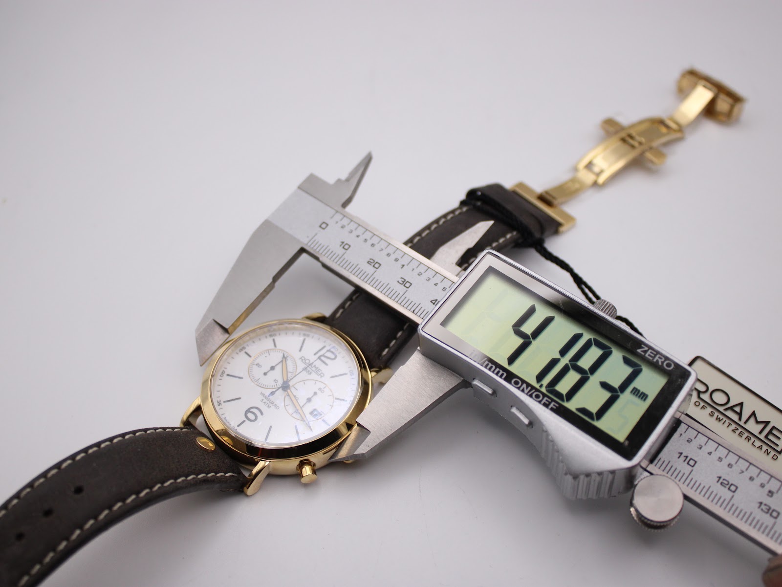 Watch case being measured by a digital caliper, displaying "41.83 mm" for the case diameter. The strap and clasp are visible in the background.
