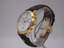Angled side view of the Roamer Vanguard watch, showing the gold case, crown, pushers, and brown leather strap on a clear stand.