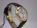 Another angled view of the watch, highlighting the white dial, gold case, and the brown leather strap with a hang tag.