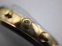 Macro shot of the gold-toned fluted crown with the Roamer 'R' logo engraved on it.