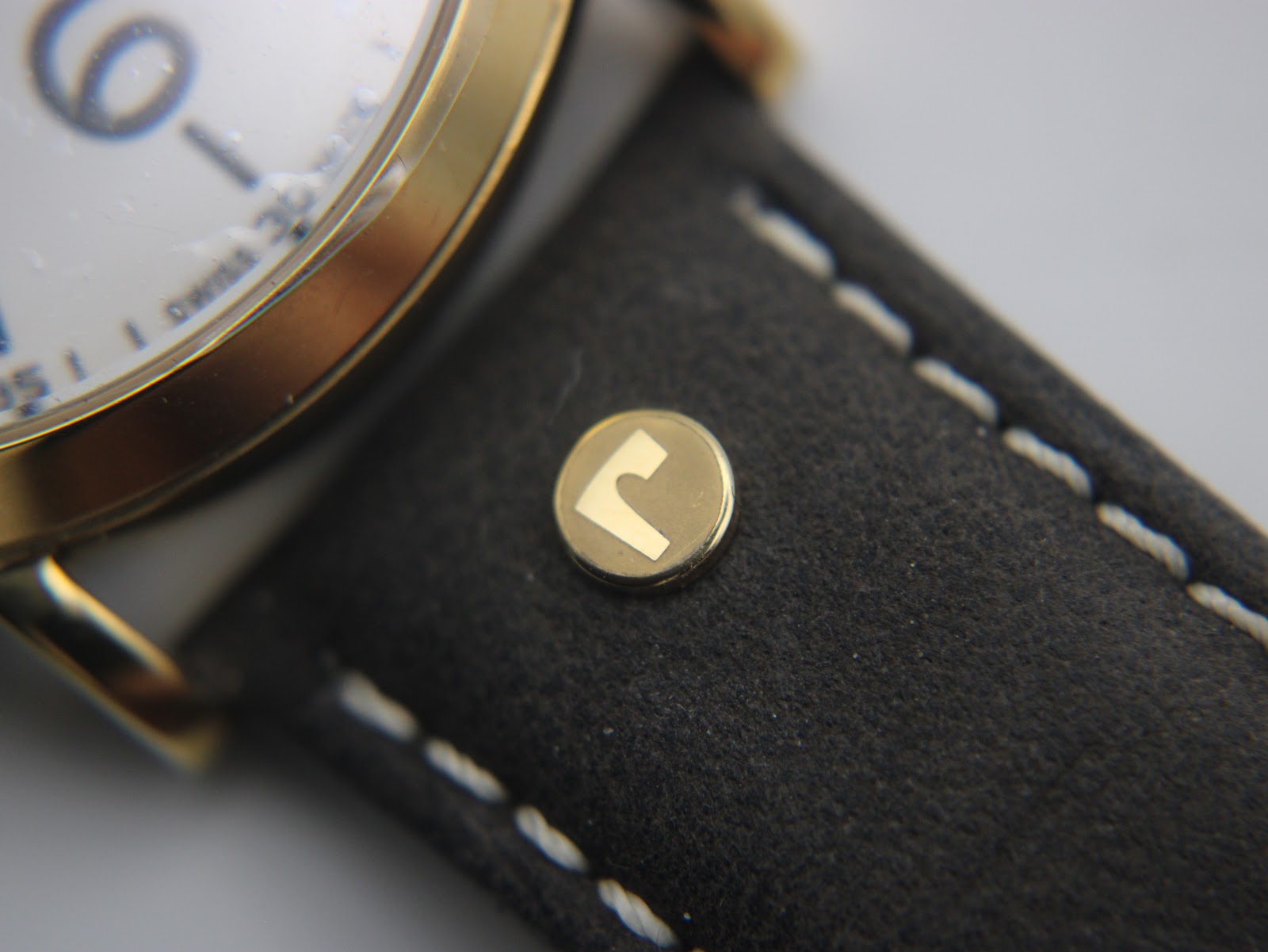 Close-up of the brown leather strap showing a gold-toned rivet with the Roamer 'R' logo.