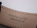 Interior view of the brown leather strap, stamped "Genuine Leather Handcrafted".