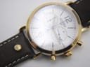 Close-up of the white chronograph dial, showing sub-dials, numerals, hands, and minute track. Reflections on the crystal.