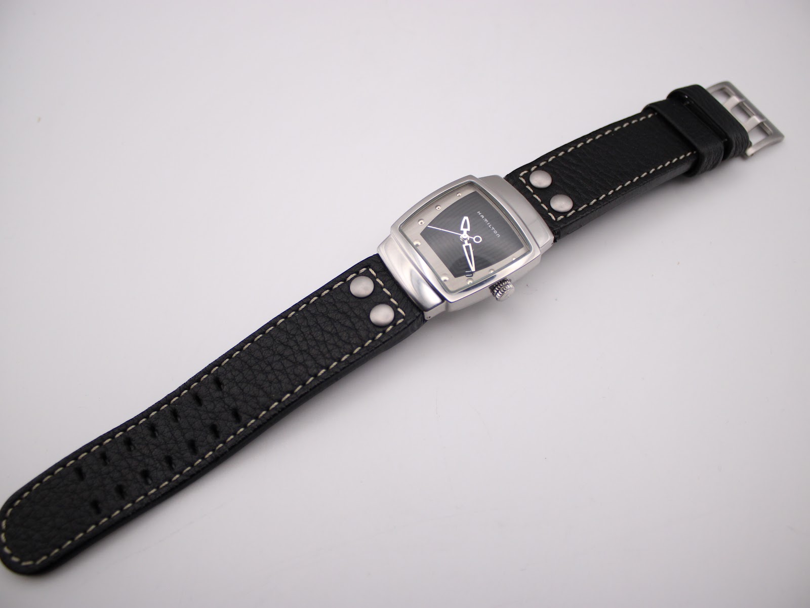 Full length view of the Hamilton H163110 watch with its black leather strap extended.
