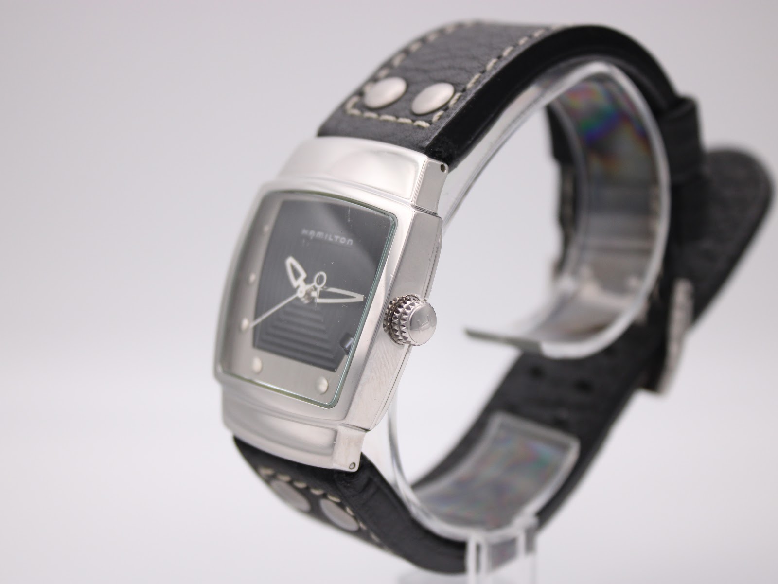 Angled side view of Hamilton H163110 watch, showing crown detail and curved tonneau case on a display stand.