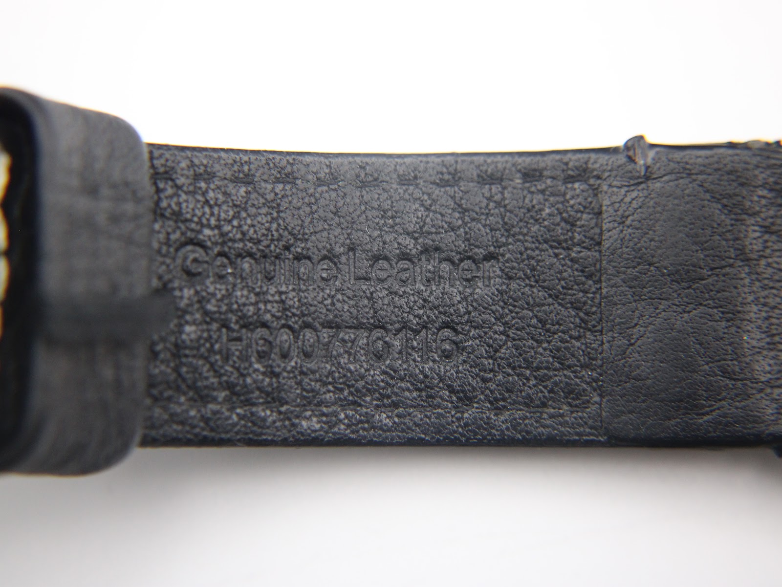 Close-up of the underside of the black leather strap, showing 'Genuine Leather' and a reference number H600776116.