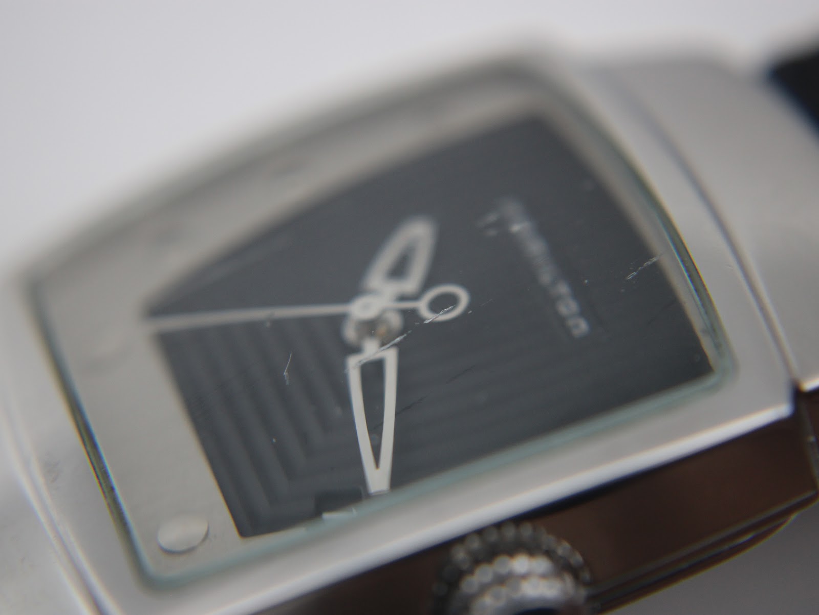 Extreme close-up of Hamilton H163110 crystal, showing small scratches on the glass surface.