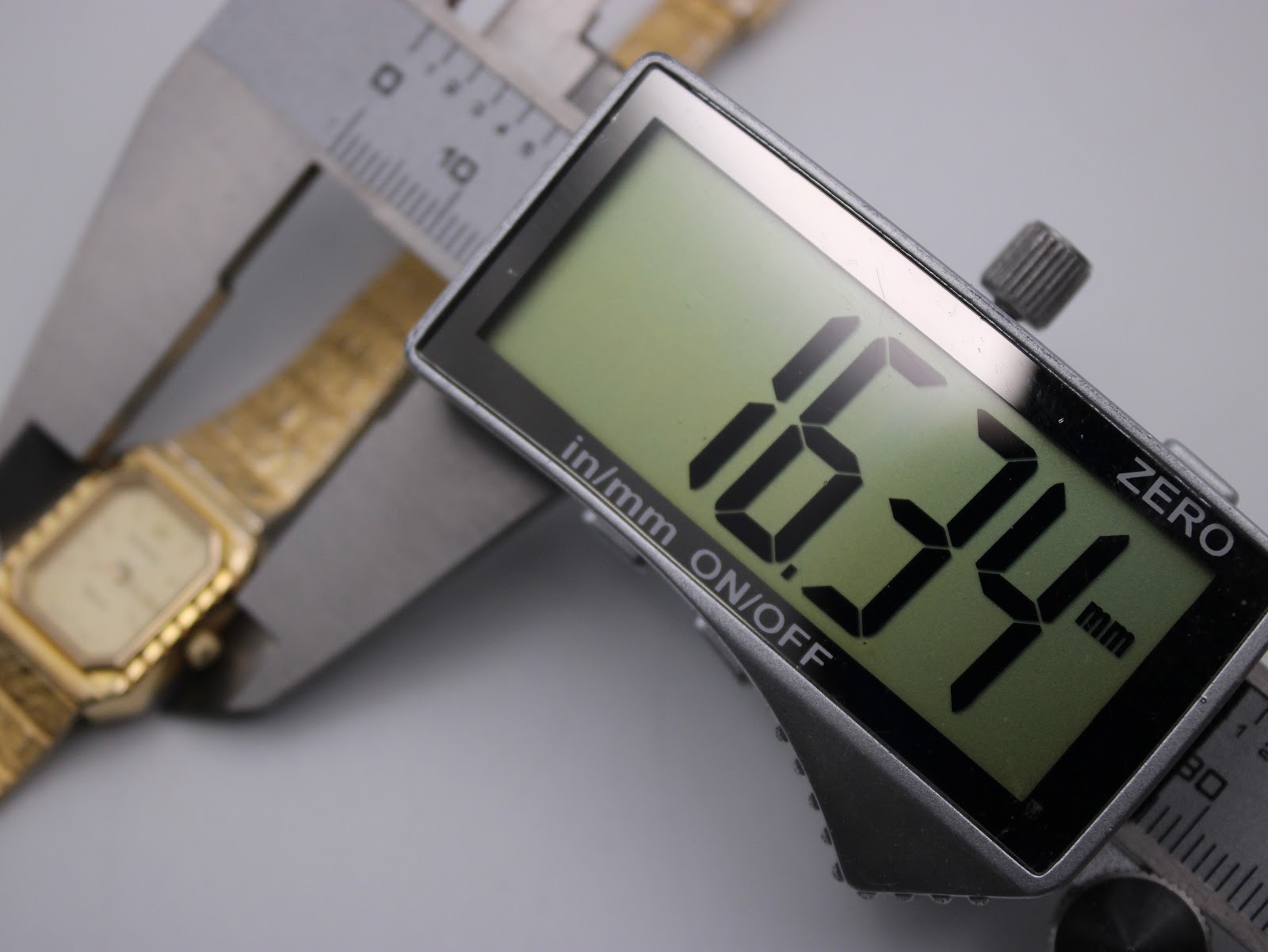 Close-up of a digital caliper measuring the watch case, displaying a precise diameter of 16.34mm.