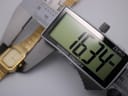 Close-up of a digital caliper measuring the watch case, displaying a precise diameter of 16.34mm.