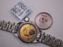 Front view of two-tone Tissot PR 50 quartz watch with white dial and gold Roman numerals on a grey background.