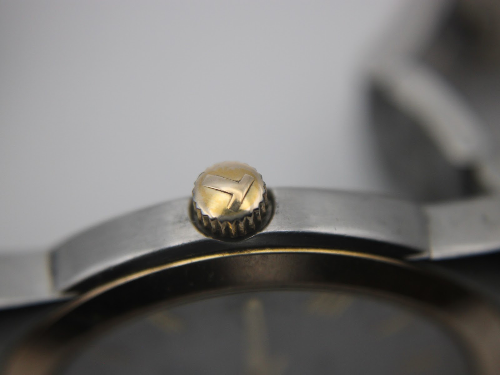 Macro shot of the gold-tone crown of the Tissot PR 50, featuring the embossed Tissot 'T' logo.