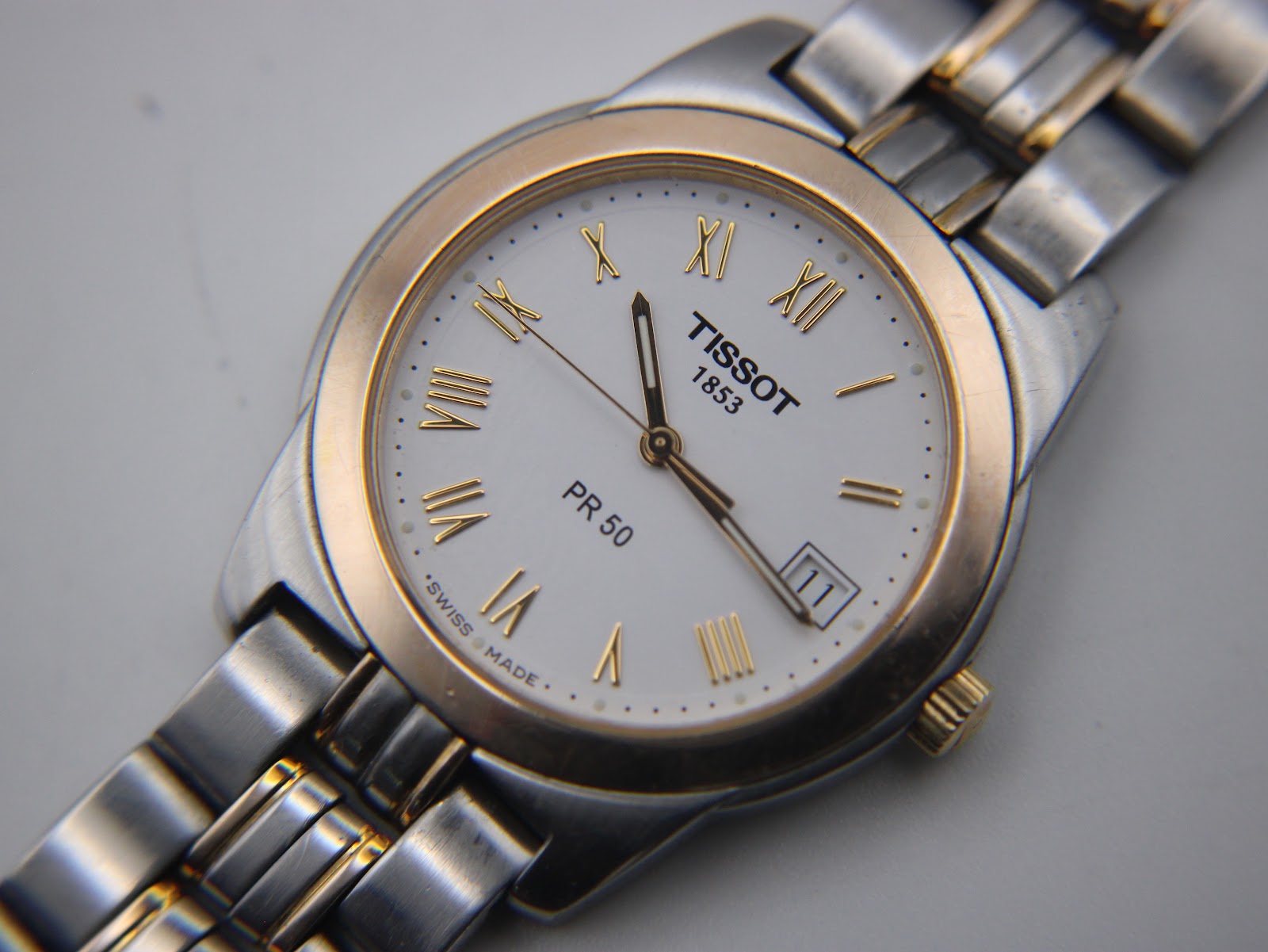 Overhead angled view of the Tissot PR 50 watch, showcasing the full two-tone bracelet.